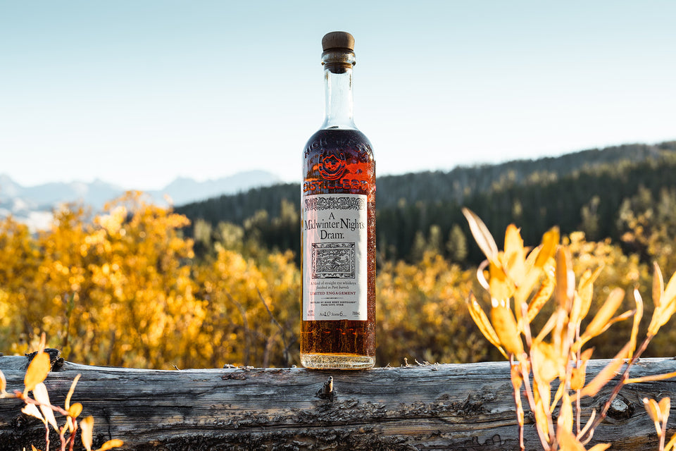 Bottle of midwinters night dram on a log with mountains in the background